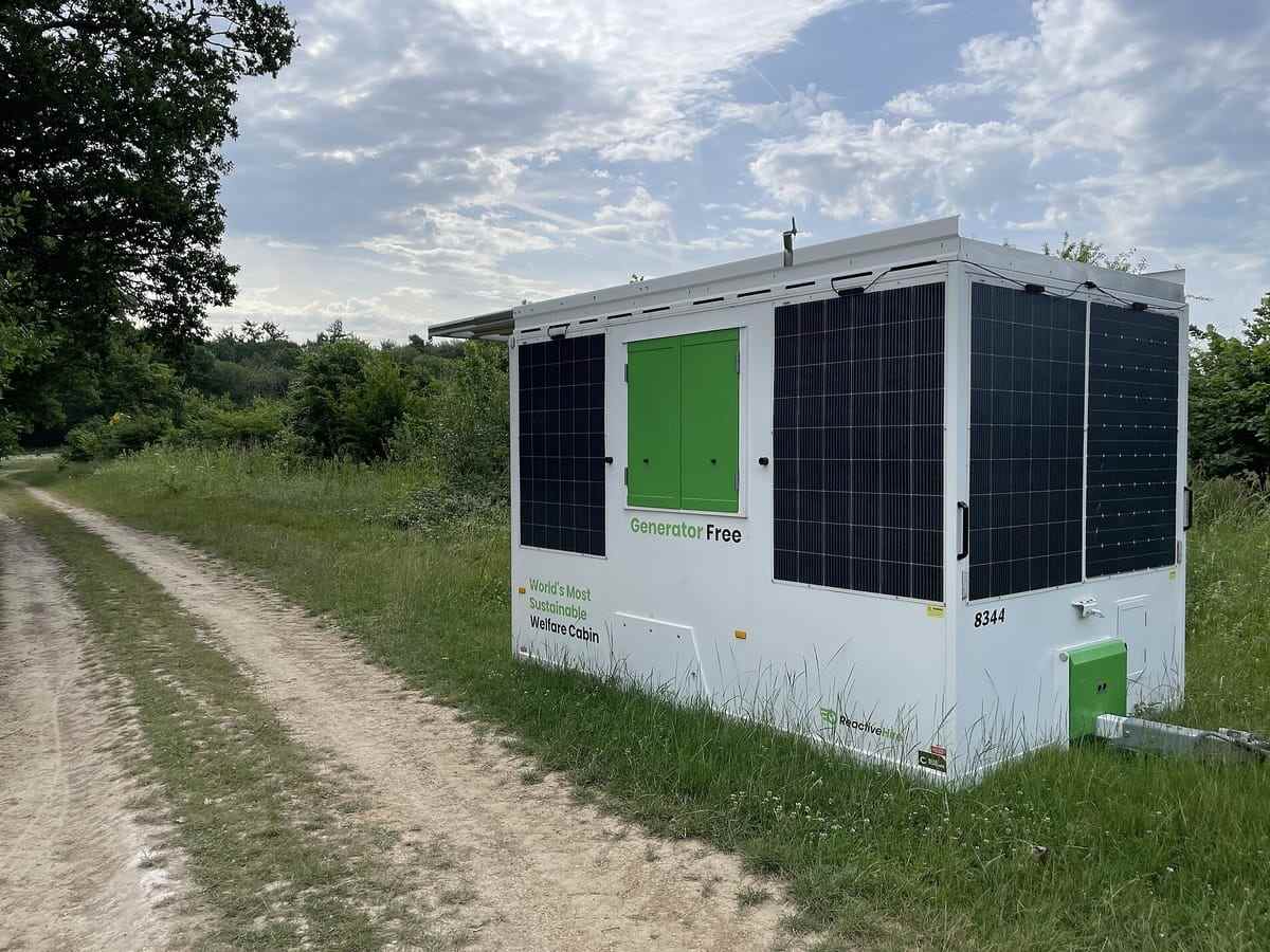 A solar-clad site welfare cabin standing on a track at the edge of a field