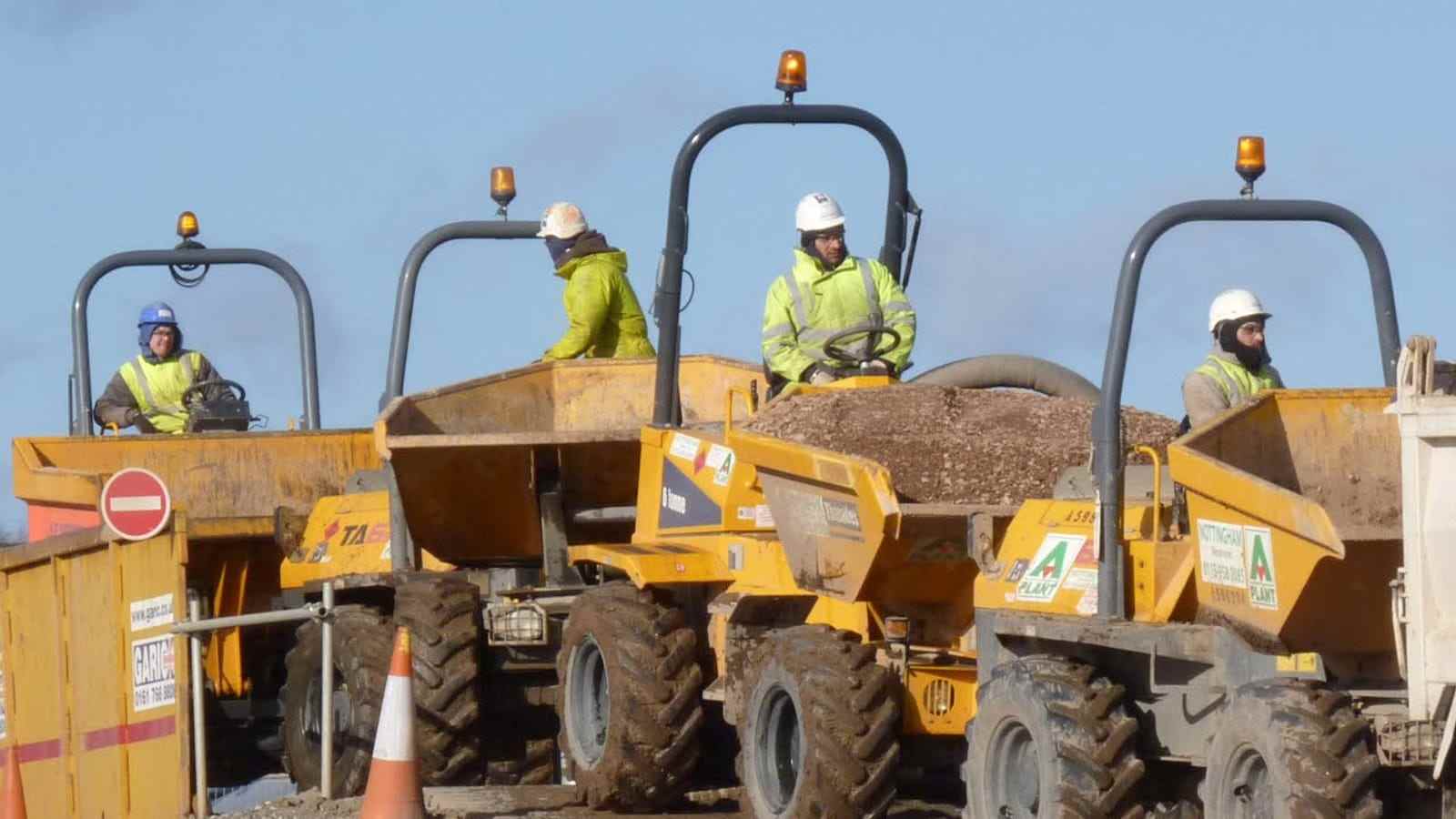 Three operators sitting on site dumpers at the start of a shift